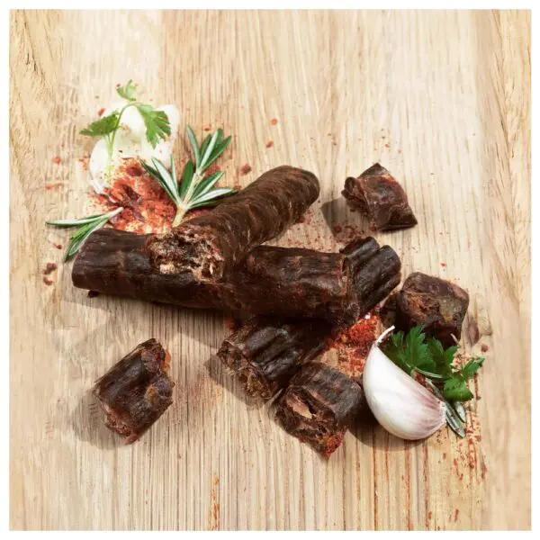 Canterbury biltong Italian Biersticks arranged on a wooden surface with herbs and garlic.