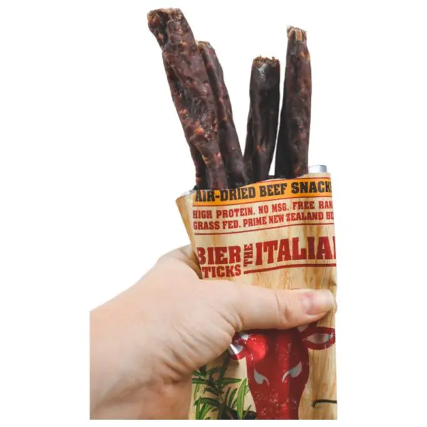 Hand holding a packet of Canterbury Biltong Italian Biersticks with three sticks visible.