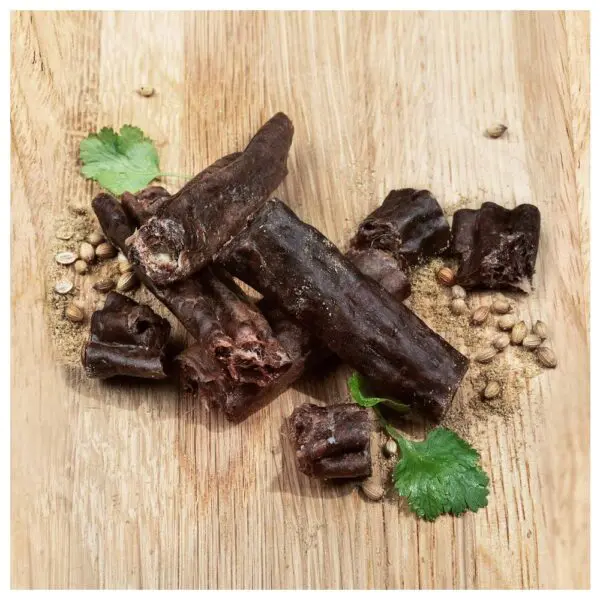 A pile of Canterbury biltong original biersticks arranged on a wooden surface with coriander leaves and spices.