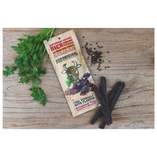 Packaging of Canterbury Biltong Biersticks Original with biltong sticks and herbs on a wooden surface.