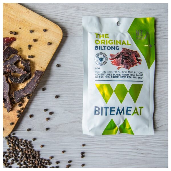Packaging of BiteMeat Original Biltong with dried biltong pieces and peppercorns on a wooden surface.