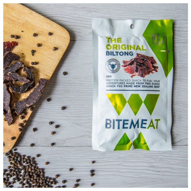 Packaging of BiteMeat Original Biltong with dried biltong pieces and peppercorns on a wooden surface.