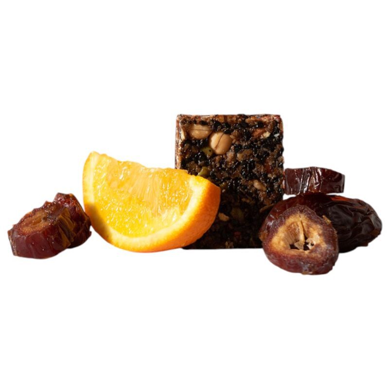 A square piece of date and orange snack with slices of orange and whole dates beside it.
