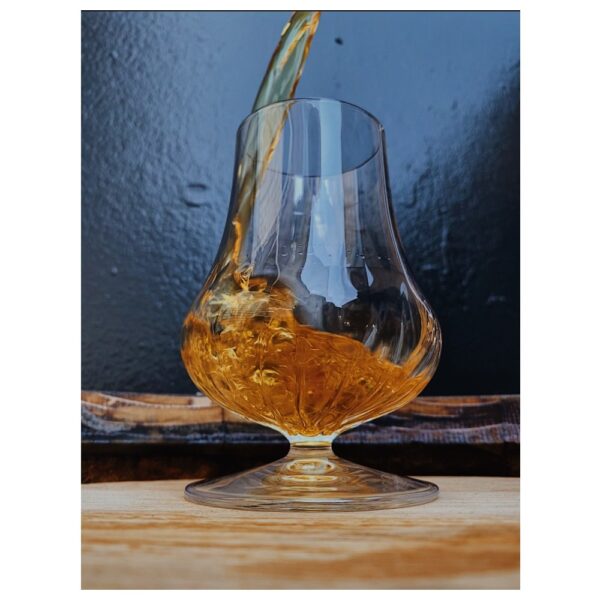Whisky being poured into a Glencairn glass, showcasing the amber liquid inside.