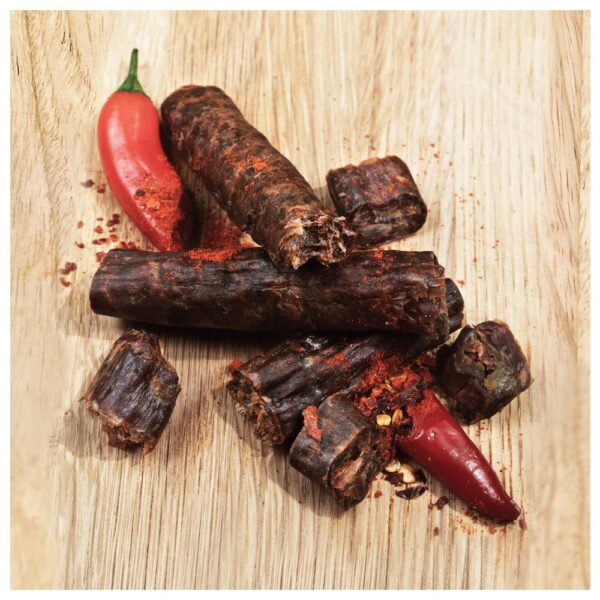 Chilli biltong biersticks arranged on a wooden surface with a red chilli pepper.